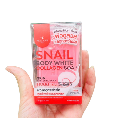 Hand holding a package of Snail Body White Collagen Soap with visible branding on a white background